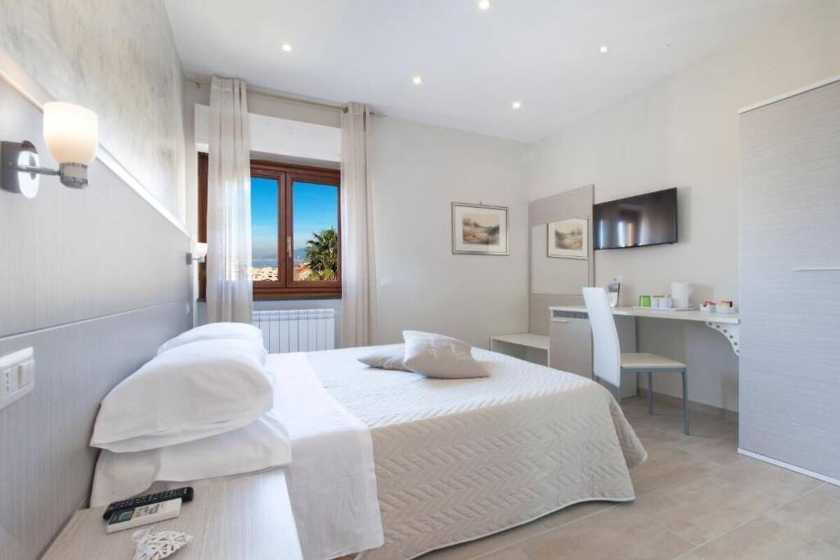 A modern hotel room with a large bed, a desk, and a TV.