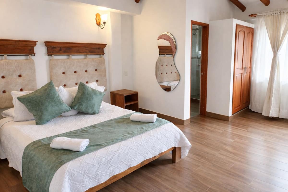 Ein Schlafzimmer mit Bett, Holz-Kopfteil, Nachttisch und einem Spiegel an der Wand.