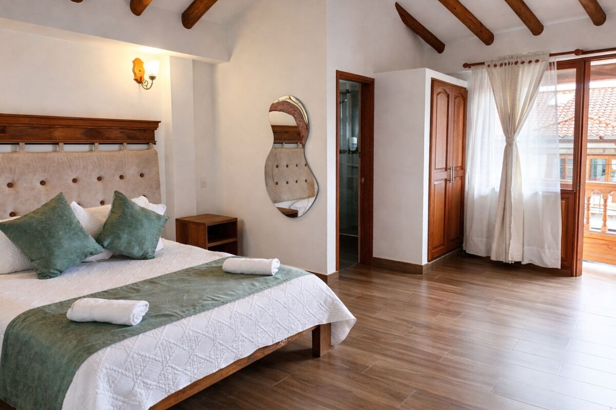Une chambre avec un grand lit, une tête de lit en bois et un plancher en bois.