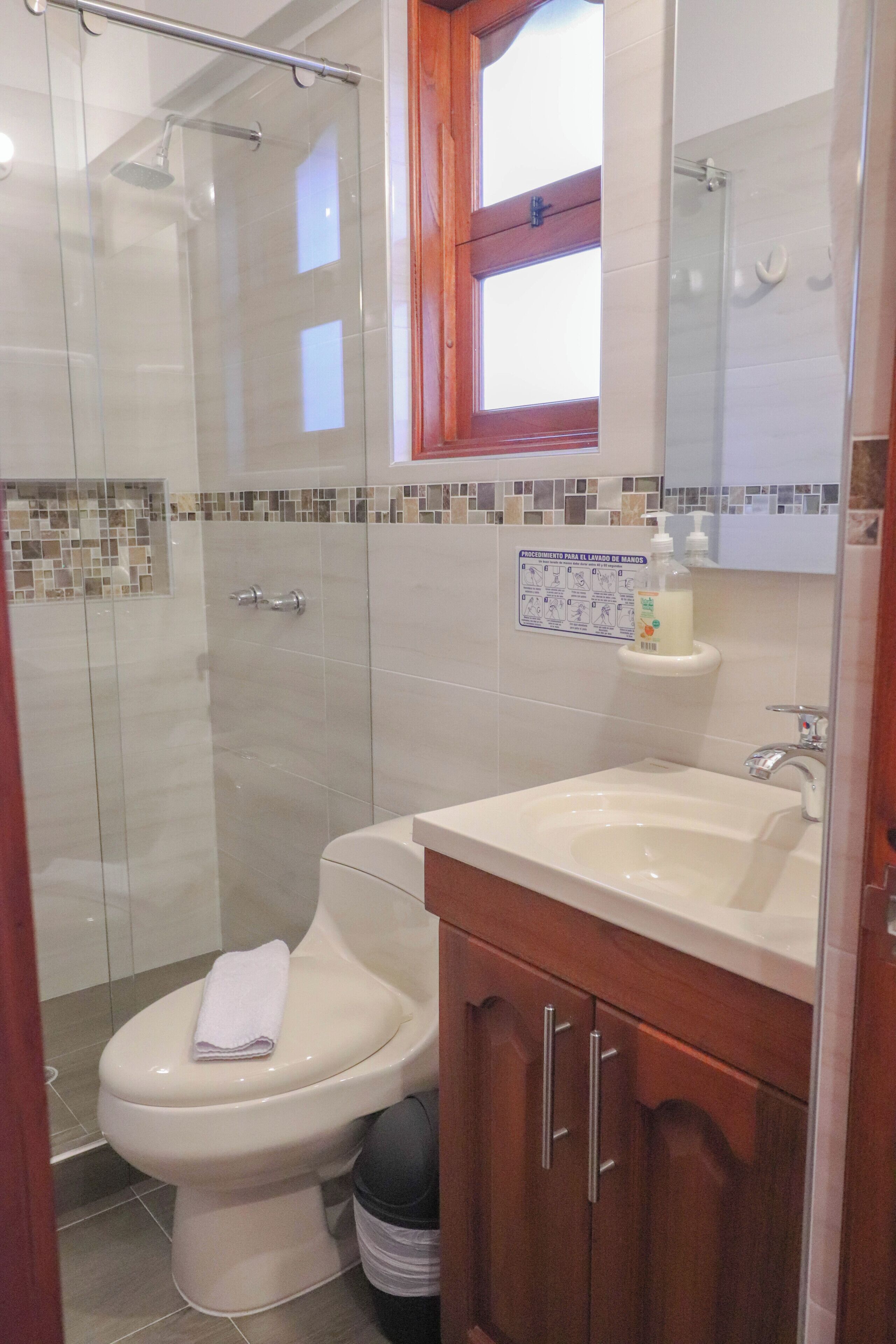 Un baño con inodoro, lavamanos, ducha y espejo.