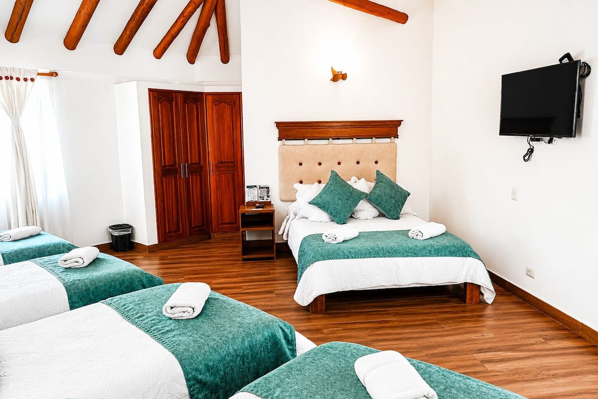 Ein Hotelzimmer mit Bett, Fernseher, Holzbalken, Kleiderschrank und Mülleimer.