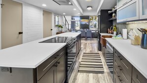 A modern kitchen with a central island, built-in appliances, and a dining area with a view.