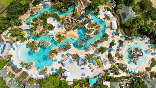 An aerial view of a resort with multiple swimming pools, lounge areas, and palm trees. - Reunion Resort Villa: Private Pool, Full Amentiy Access (Reunion)