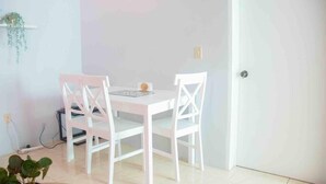 Un petit coin repas avec une table blanche et deux chaises blanches.