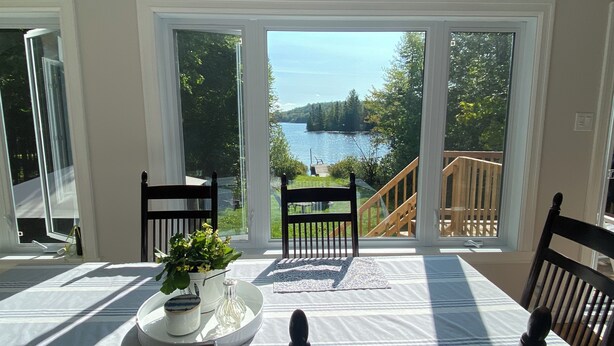 Ein Essbereich mit Tisch für zwei Personen mit Blick auf einen See und eine Terrasse.