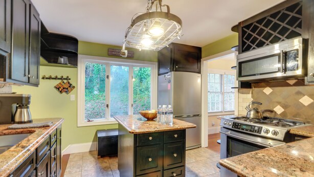 A modern kitchen with granite countertops, stainless steel appliances, and a central island with drawers.