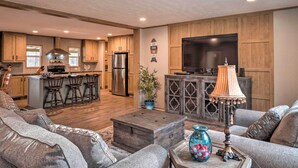 A spacious living room with a large sofa, a coffee table, and a TV in the background. - 'Bayside' Louisiana Vacation Rental w/ Dock! (Many)