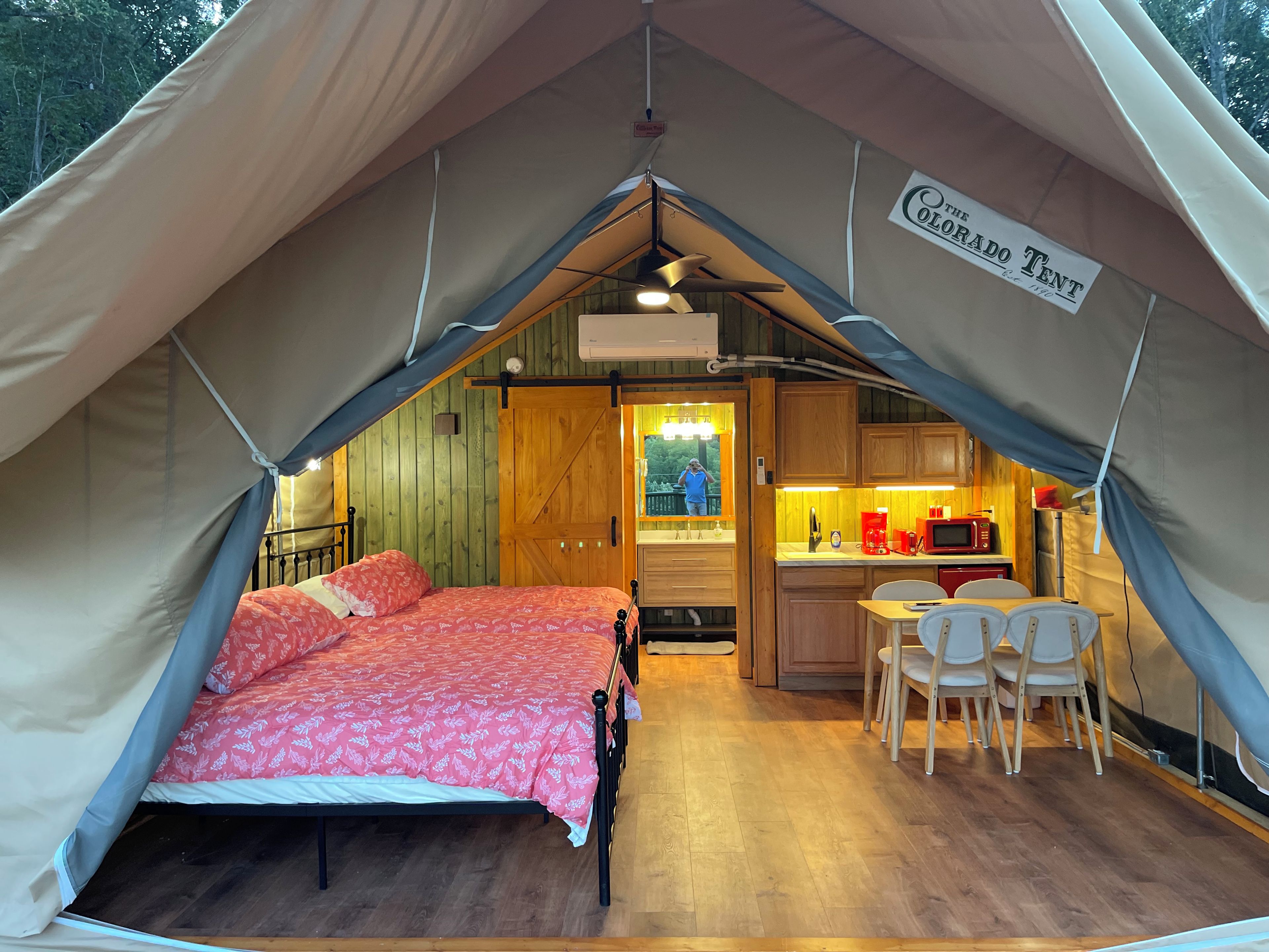 Une tente équipée d’un lit, d’une petite kitchenette et d’un coin repas.