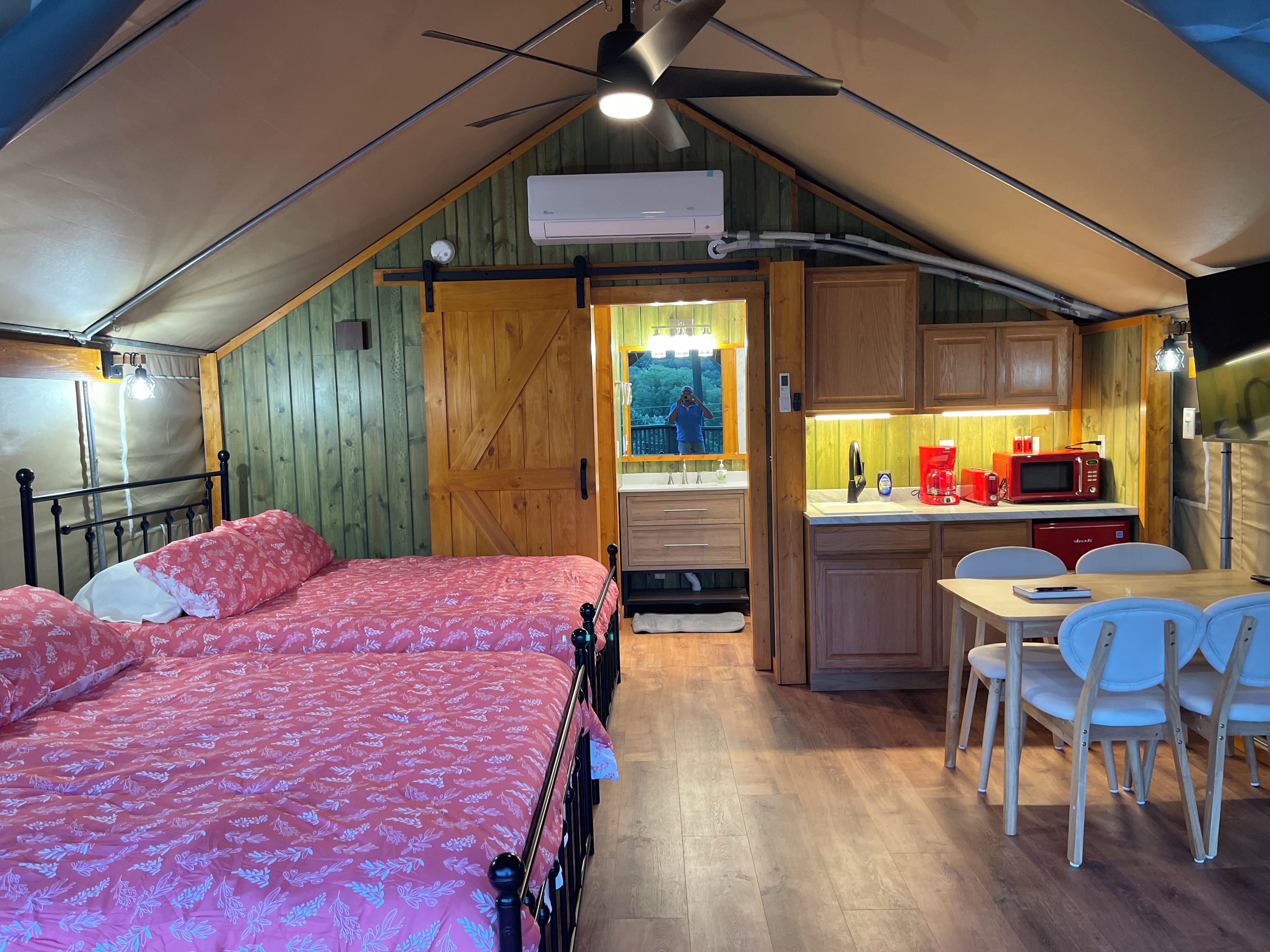 A cozy bedroom with a large bed, a wooden door, and a kitchenette with a microwave and sink.