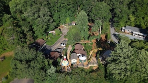 An aerial view of a residential area with multiple houses, a playground, and a large water tank. - Mountain Aire Cottages, Inn & Glamping (Clayton)