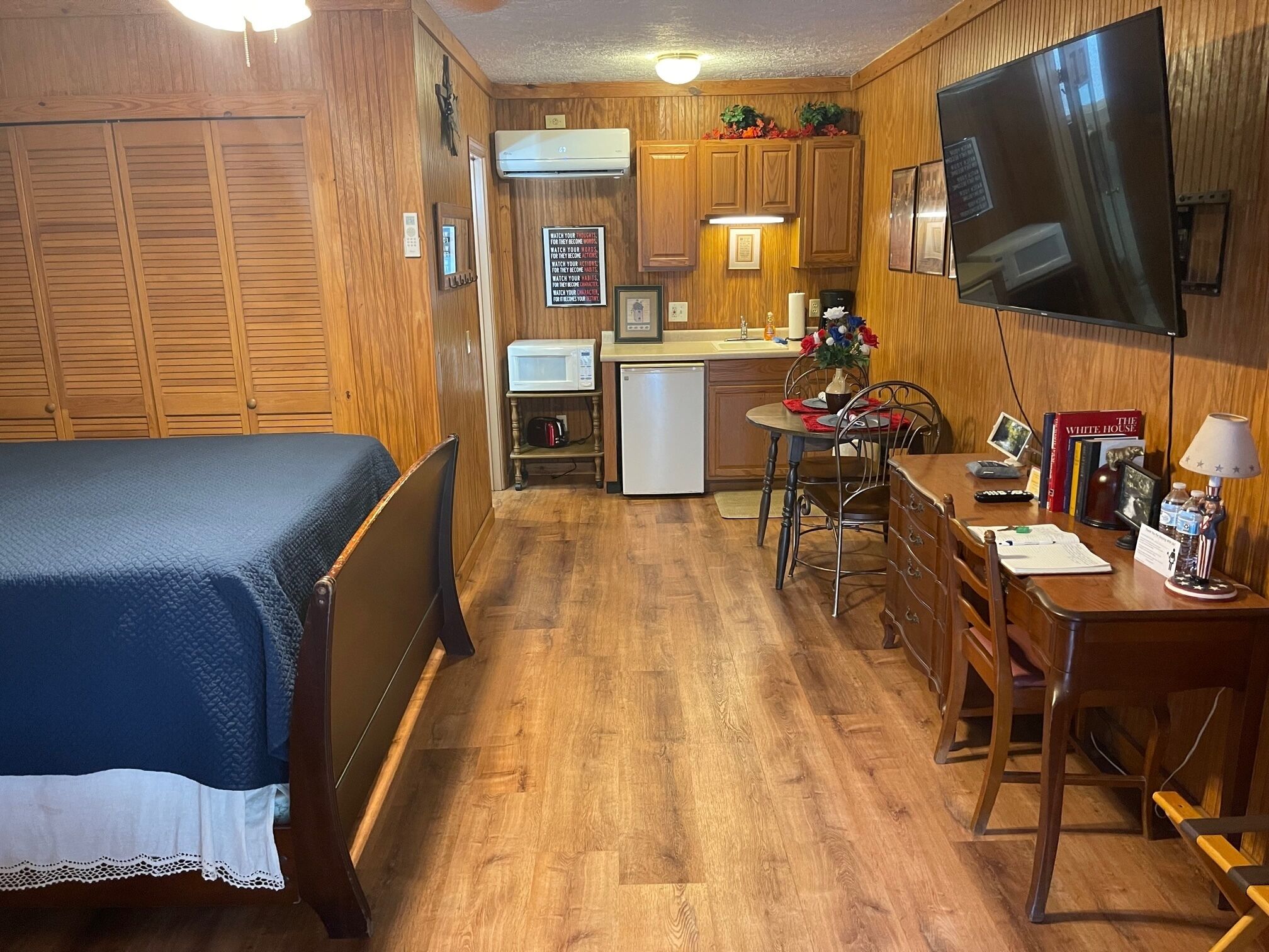 A compact room with a bed, kitchenette, dining area, and a TV.