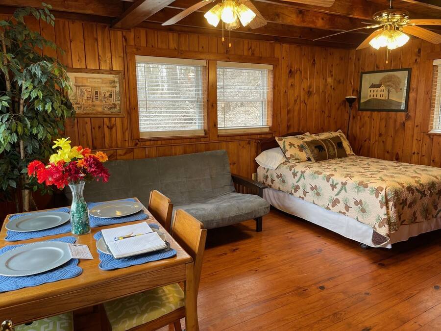 Una cabaña de madera con comedor, sofá y cama.