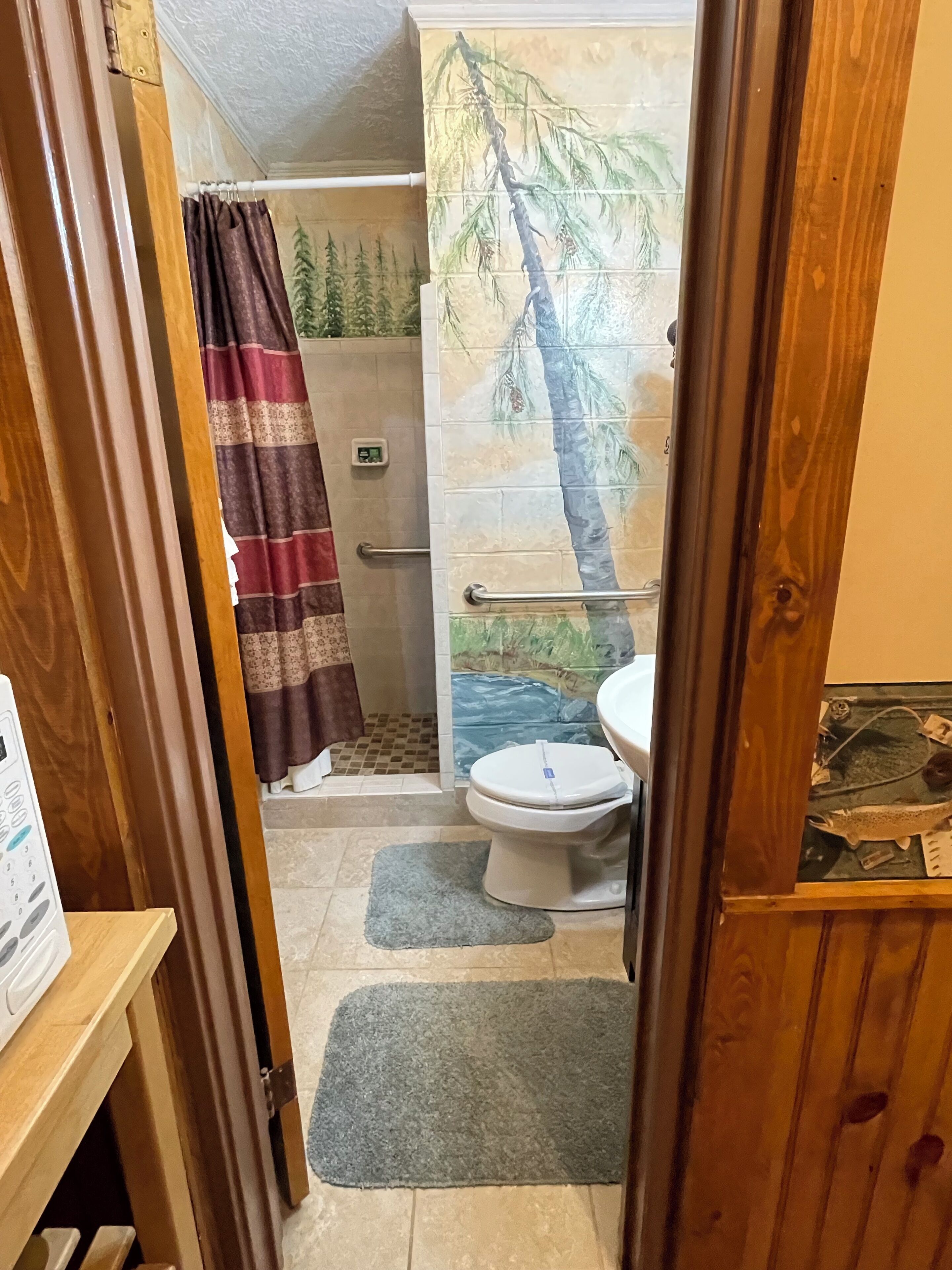 A bathroom with a shower, toilet, and a towel rack.
