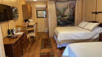 A cozy room with wooden walls, a bed with white bedding, a desk with a chair, a television, and a painting on the wall.