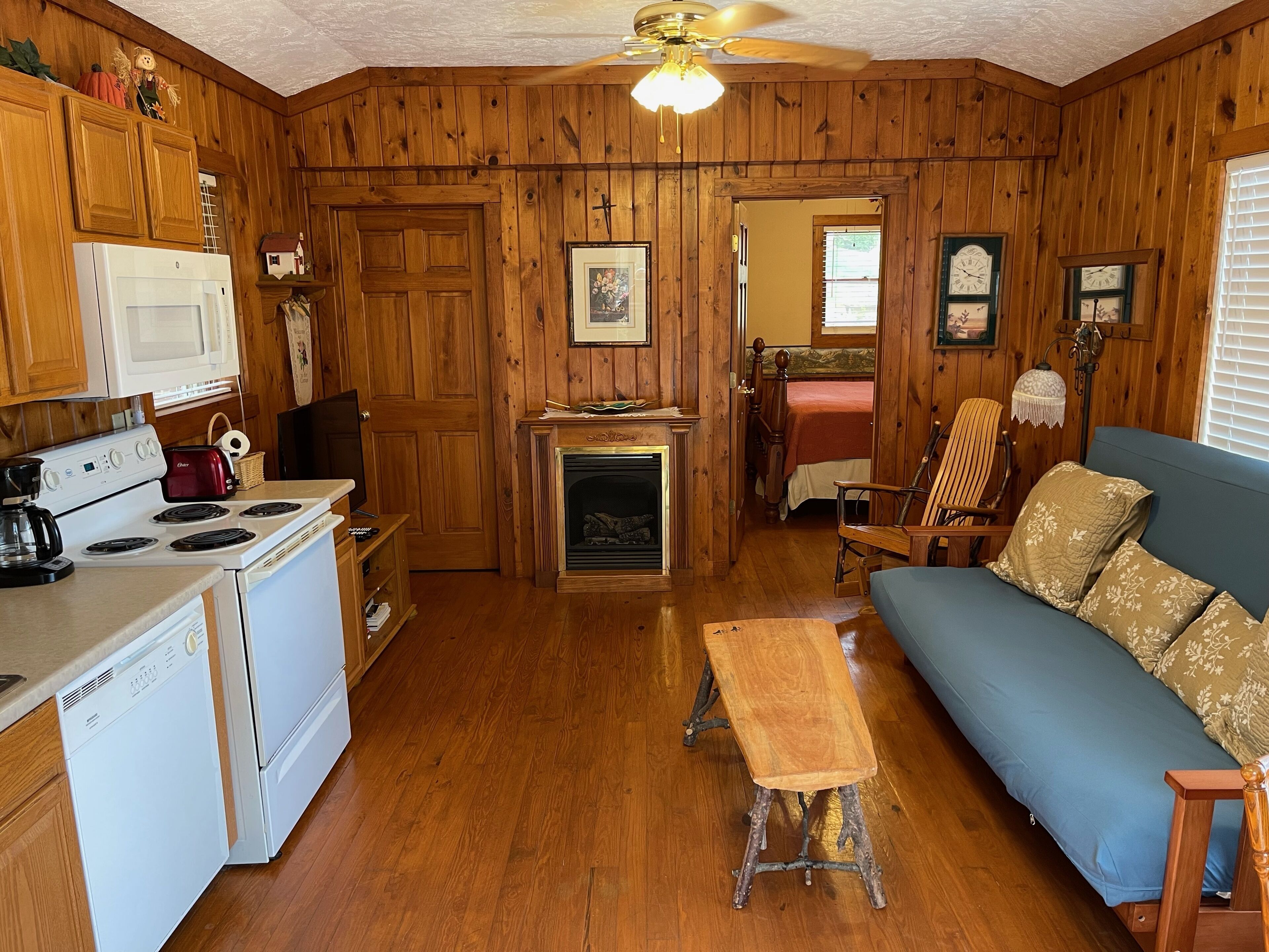 Une pièce confortable, aménagée comme un chalet, avec des murs en bois, une cheminée, un coin repas et un salon doté d’un canapé et d’un banc.