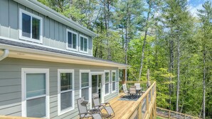 A two-story house with a deck, outdoor furniture, and a view of a forest. - 3 King Bedrooms with Hot Tub Game Room Fire Pit Pool Table Putting Room (Townsend)