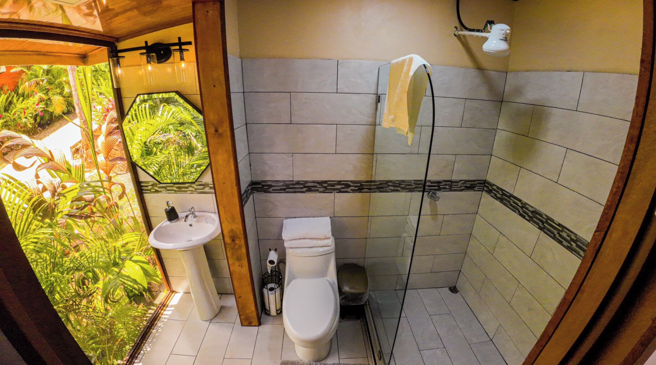 Un baño con inodoro, lavabo, ducha y vistas al exterior.