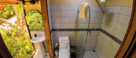 Un baño con inodoro, lavabo, ducha y vistas al exterior.