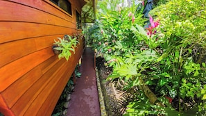 A wooden exterior wall with a pathway leading to a garden area. - Bungalows Las Iguanas Arenal Volcano (Peñas Blancas)