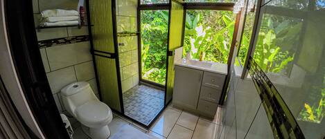 Un baño pequeño con inodoro, cabina de ducha y lavabo.