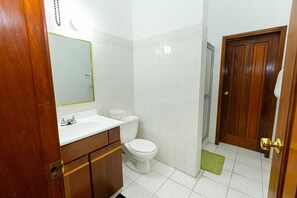 A bathroom with a white sink, toilet, and shower area.