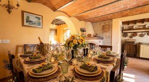 Un coin repas avec un plafond en briques, une table dressée et un vase rempli de fleurs.