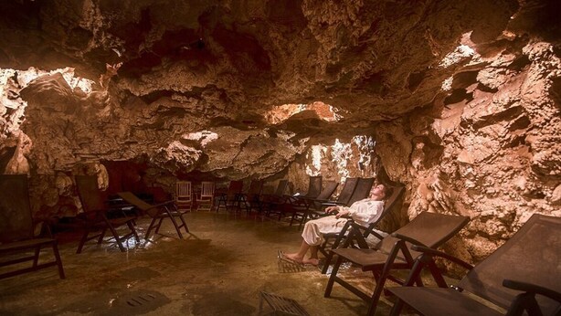 A cave interior with wooden chairs, a person sitting, and natural rock formations. - The Domo farmhouse and its ancient charm (Toscana)