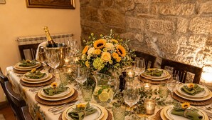 A dining table set with plates, glasses, and a pitcher, surrounded by chairs and a stone wall. - The Domo farmhouse and its ancient charm (Toscana)