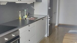 A modern kitchen with grey cabinets, stainless steel appliances, and a wooden floor. - Apartment in Sundbyberg , Stockholm (Sundbyberg)