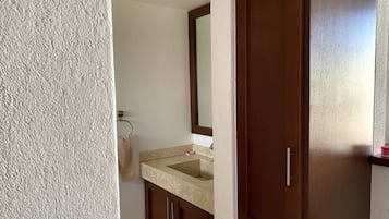 Un baño con lavamanos de encimera color beige, un espejo y armarios de madera.