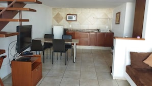 Um espaço compacto com área de refeições, cozinha americana e um pequeno espaço para sentar.