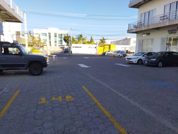 A parking area with marked spaces and a building with a yellow facade in the background.