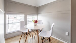 A modern dining area with a round white table, four white chairs, and a vase with flowers. - 8037-Walk to Mayo- Loft apt in the middle of Mayo campus (Rochester)
