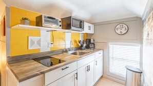 A kitchen with yellow and white tiles, a microwave, a toaster, and a clock on the wall. - 8037-Walk to Mayo- Loft apt in the middle of Mayo campus (Rochester)