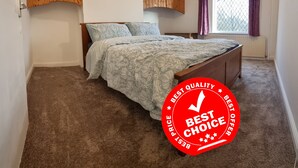 A bedroom with a bed, wooden wardrobe, and a window with curtains. - 3 Bedroom House in Central Rochdale cul-de-sac Free Parking & Fast Wi-Fi (Rochdale)