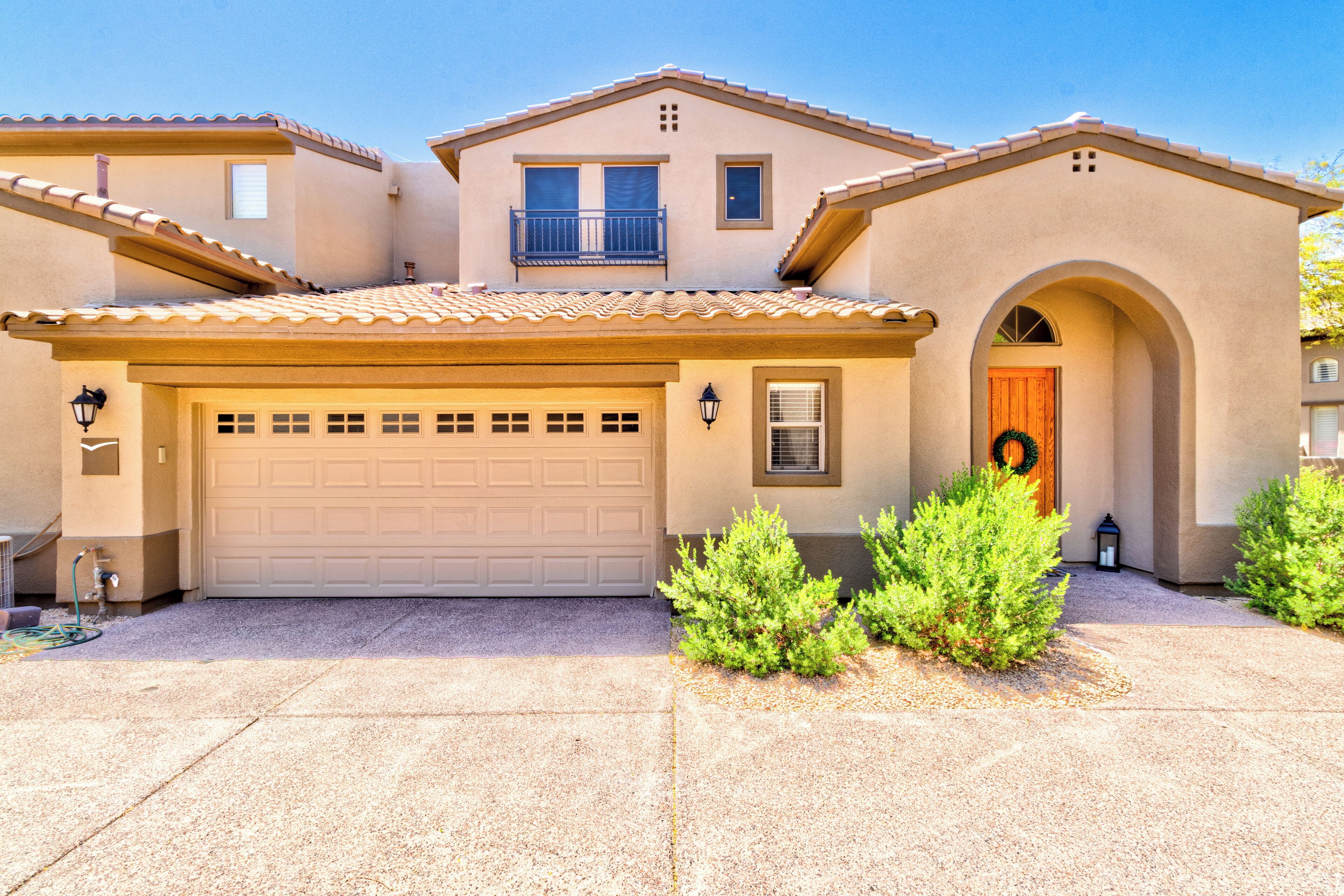 A two-story house with a beige facade, a garage, and a front entrance with a wreath.