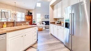 A modern kitchen with white cabinetry, a stainless steel refrigerator, and a large island with a sink. - Beautiful Guard Gated Grayhawk Townhome - Available Dates> March 30-April 19! (Scottsdale)