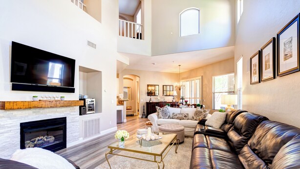 A spacious living room with a fireplace, leather sofa, and a flat-screen TV mounted on the wall. - Beautiful Guard Gated Grayhawk Townhome - Available Dates> March 30-April 19! (Scottsdale)