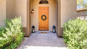 A stucco building with a wooden door, a welcome mat, and two lanterns. - Beautiful Guard Gated Grayhawk Townhome - Available Dates> March 30-April 19! (Scottsdale)
