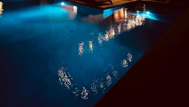 Uma casa de dois andares com piscina, fachada de madeira e iluminação interna.