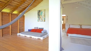 Quarto com cama beliche, rede e um quadro na parede.