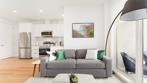 Ein modernes Wohnzimmer mit einem grauen Sofa, einem kleinen Tisch und einem Blumentopf.