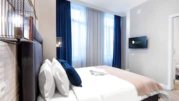 A hotel room with a bed, a TV mounted on the wall, and a window with curtains.