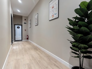 A hallway with a fire extinguisher, exit sign, and framed posters on the wall. - Degoya Studios Bucharest Oldtown (Bucharest)