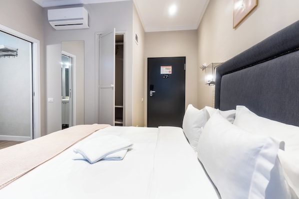A hotel room with a bed, a wardrobe, a closet, and a door with a sign.