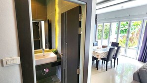 Une salle de bain moderne avec un grand miroir, un lavabo et un espace douche.