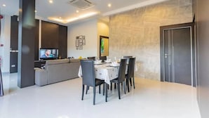 Un espace de repas moderne avec une table ronde dressée pour six personnes, un canapé et un téléviseur en arrière-plan.