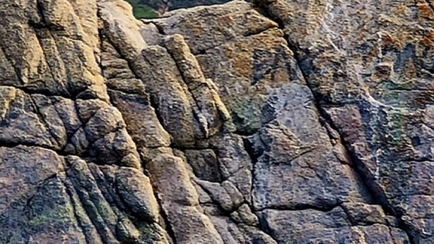 Un castillo en una colina rocosa con un muro de piedra al frente.