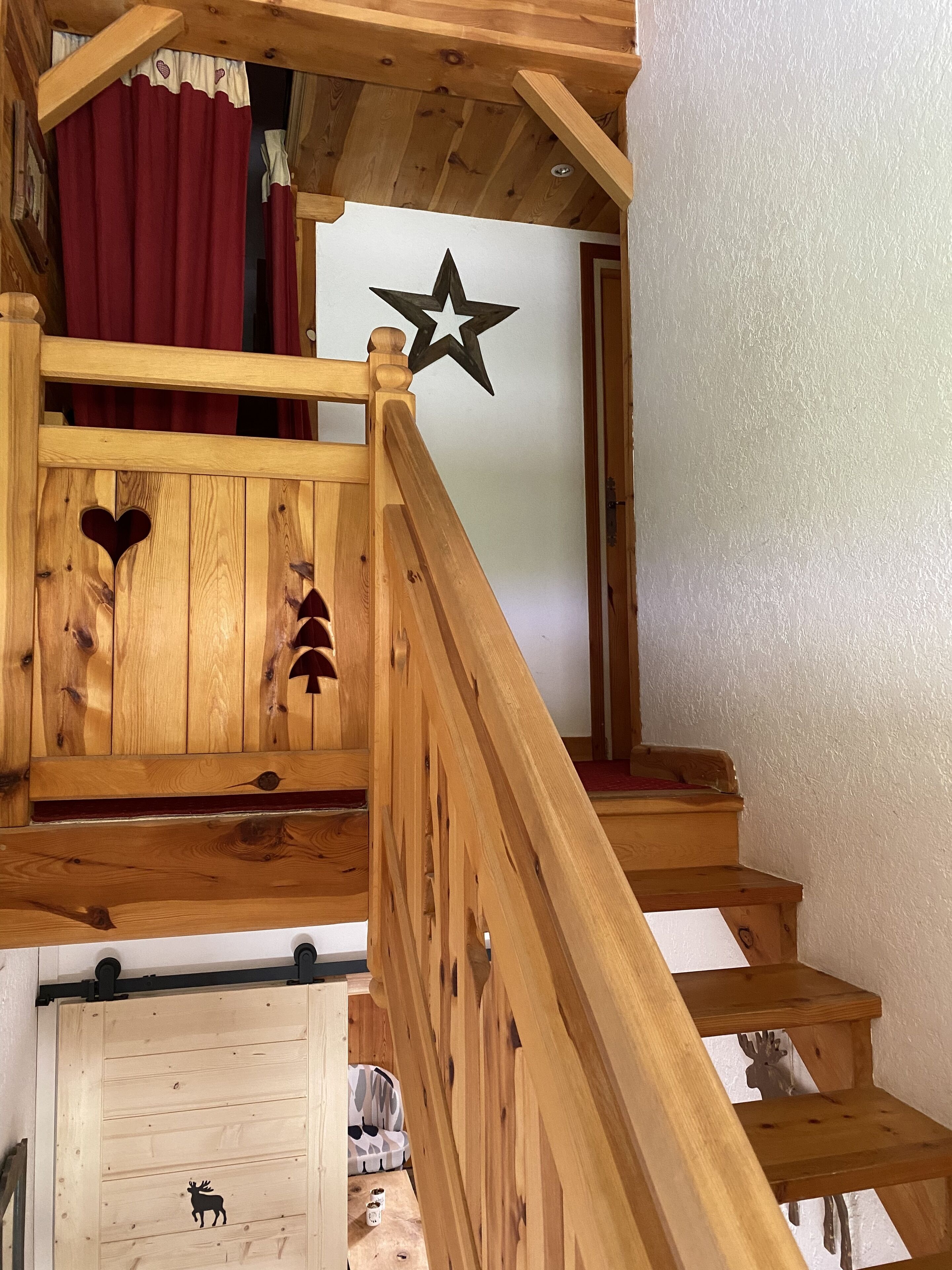 A wooden staircase with a star decoration, heart-shaped cutouts, and a moose design on the wall.