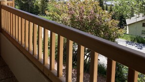 En balkon med trægelænder med udsigt over et bjerglandskab med en dal og en lille landsby.